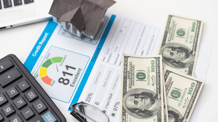 Credit report with an excellent score of 811, US dollar bills, a calculator, and a miniature house model, representing personal finance management and the importance of credit bureaus in assessing creditworthiness.