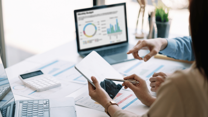 Professionals analyzing investment charts and planning 401(k) contributions using digital tools.